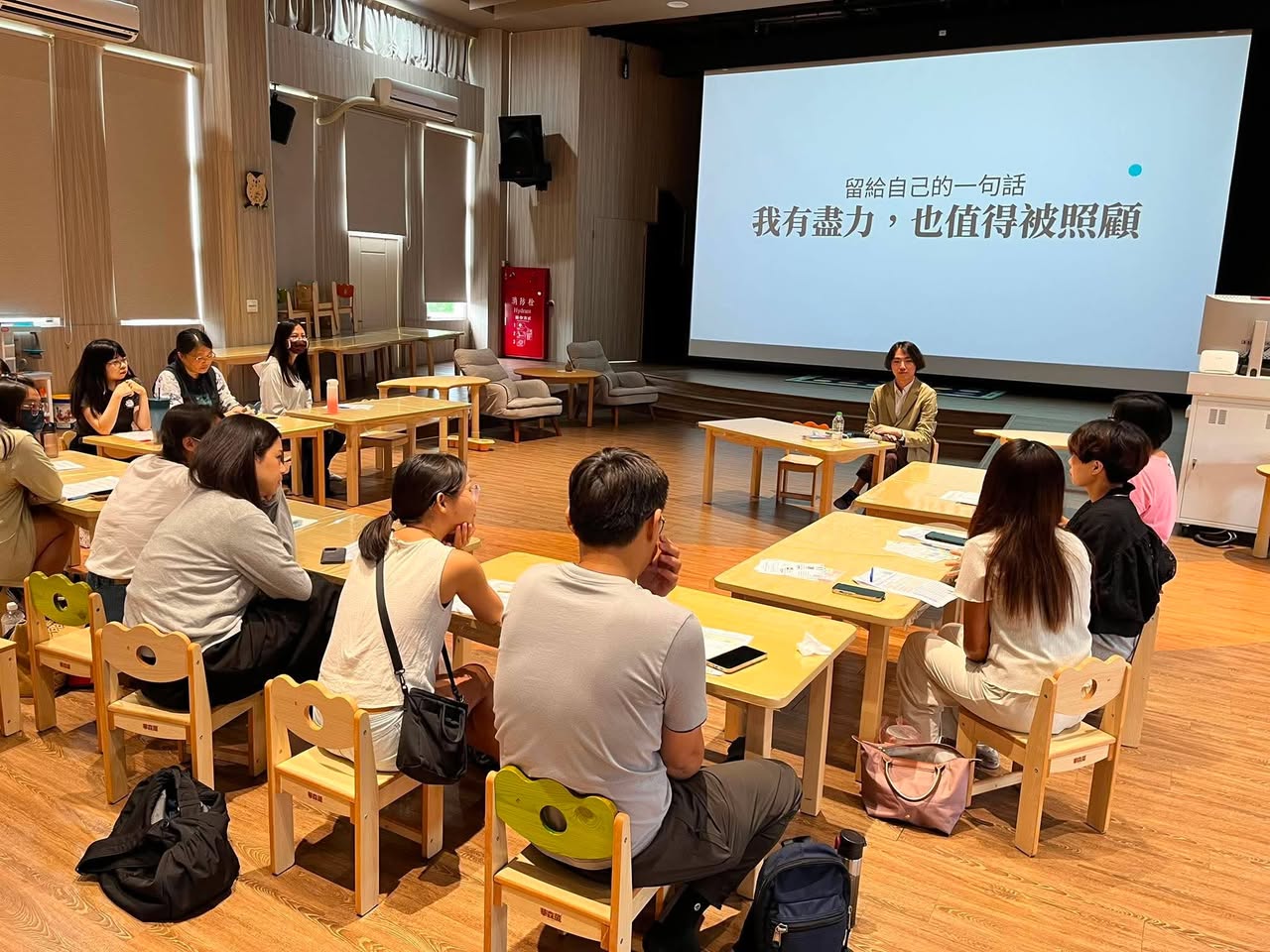 逸帆老師與家長圍坐交流，投影文字為「我有盡力，也值得被照顧」。